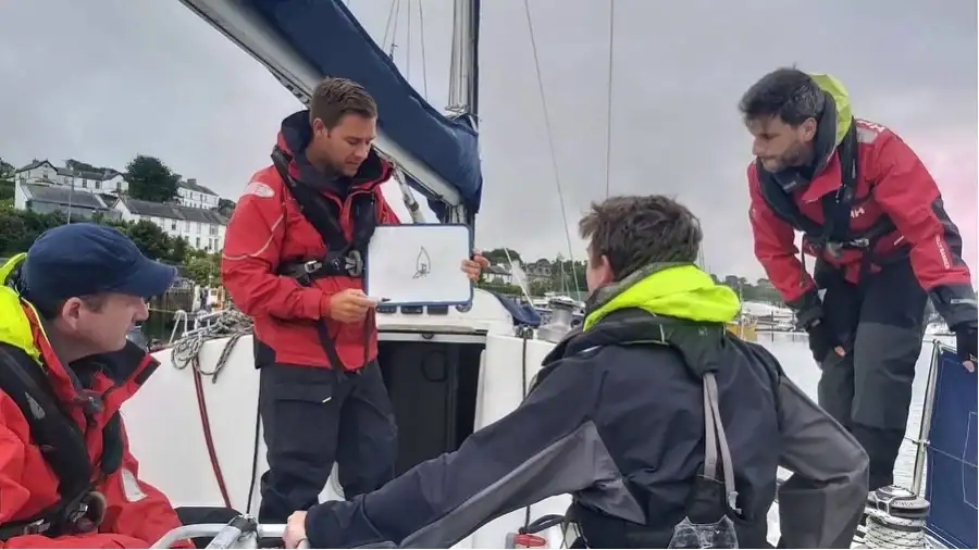 Mentor showing screen to crew on yacht