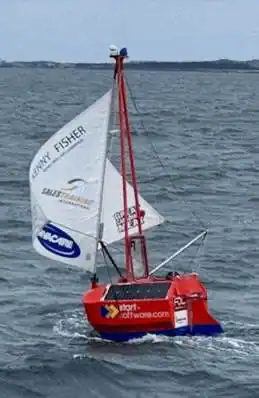 Tiny red yacht Big C under sail