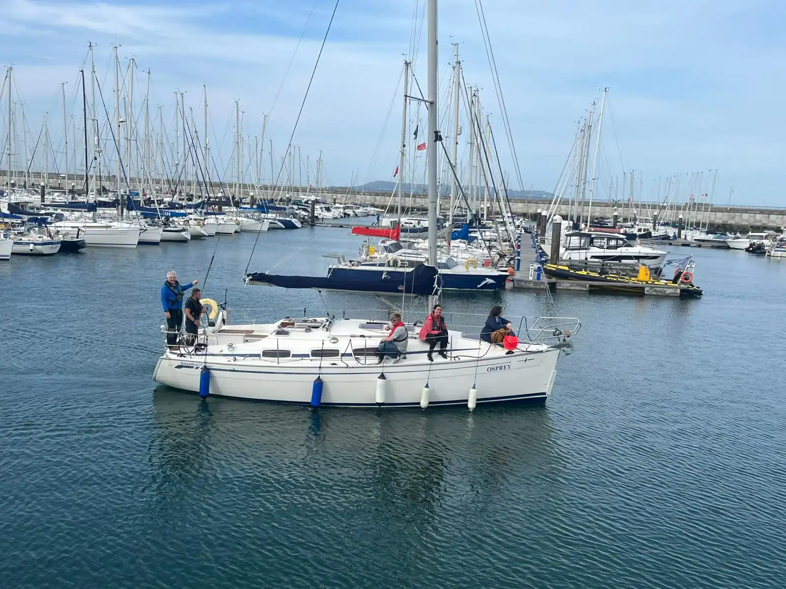 A yacht under engine approaching a marina berth