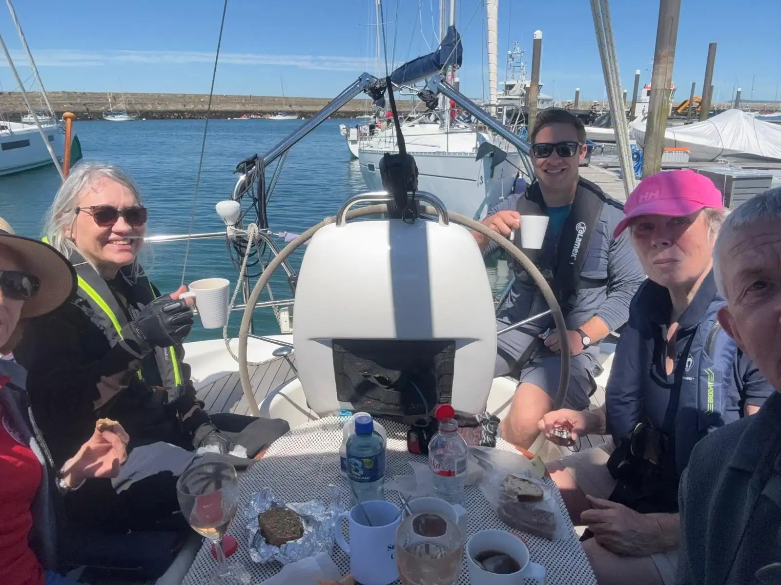 A group of sailors in the cockpit of a yacht at lunch time